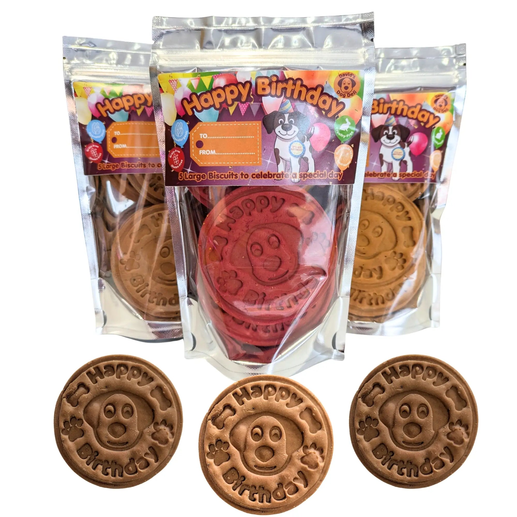 Three clear plastic bags of dog birthday biscuits with colorful 'Happy Birthday' labels, shown with three round brown biscuits in front displaying an embossed dog face and 'Happy Birthday' text.